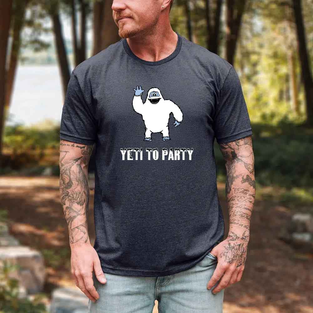 Man wearing a t-shirt with a yeti graphic and 'Yeti to Party' text in a forest setting