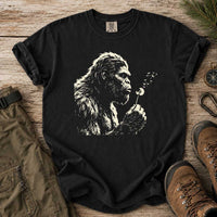 Thumbnail for May include a Black Bigfoot blowing a dandelion graphic on a casual T-shirt for men and women with a funny Sasquatch blowing wishes design.