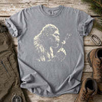Thumbnail for May include a Gray Bigfoot blowing a dandelion graphic on a casual T-shirt for men and women with a funny Sasquatch blowing wishes design.