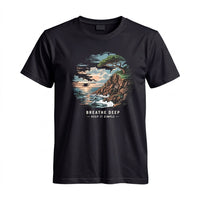Thumbnail for May include a Black Breathe Deep Keep It Simple T-Shirt featuring a scenic coastal landscape with ocean waves, rocky cliffs, a windswept tree, and an inspirational nature graphic.