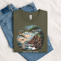 Thumbnail for May include a Military Green Breathe Deep Keep It Simple T-Shirt featuring a scenic coastal landscape with ocean waves, rocky cliffs, a windswept tree, and an inspirational nature graphic.