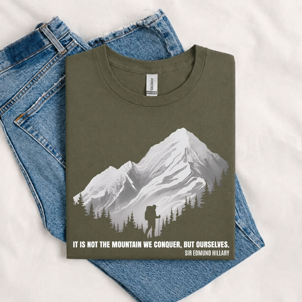 May include a Military Green It Is Not the Mountain We Conquer but Ourselves T-Shirt featuring an inspirational mountain quote graphic for hikers, climbers, campers, and mountain lovers.