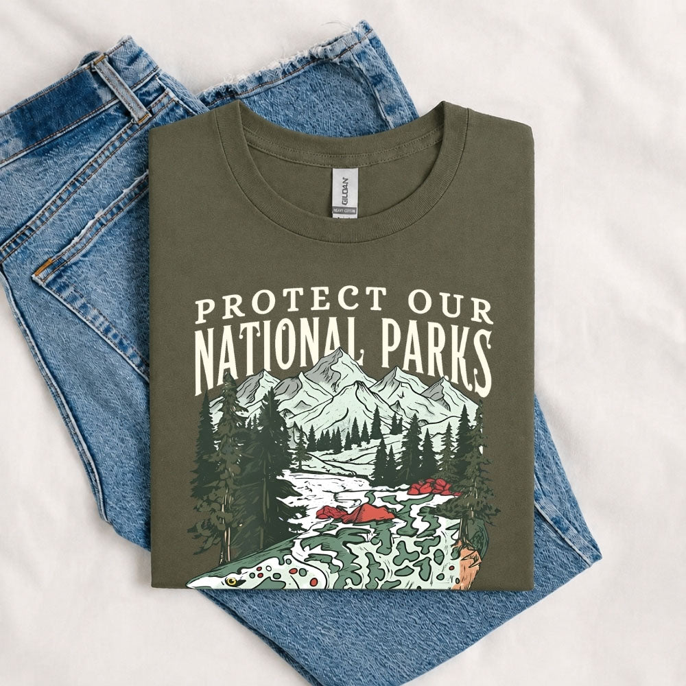 May include a Military Green Protect Our National Parks Fish X River Graphic T-Shirt featuring a fish silhouette with a scenic river landscape for anglers, hikers, campers, and nature lovers.
