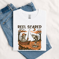 Thumbnail for May include a White person wearing the Reel Scared Halloween T-Shirt featuring a funny fishing-inspired Halloween graphic for spooky season celebrations.