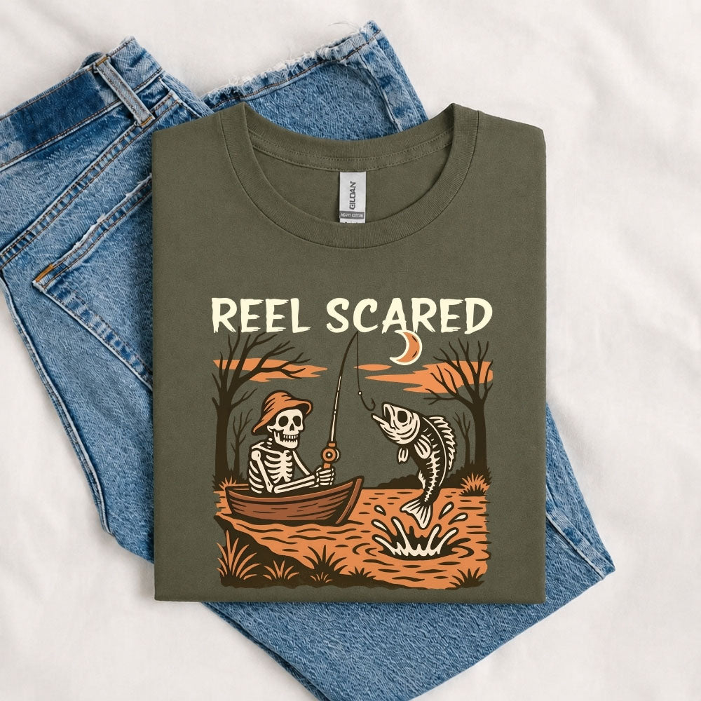 May include a Military Green person wearing the Reel Scared Halloween T-Shirt featuring a funny fishing-inspired Halloween graphic for spooky season celebrations.