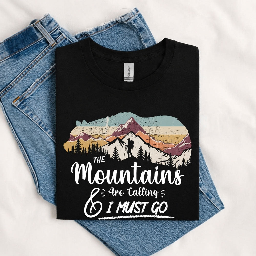 May include a Black The Mountains Are Calling and I Must Go T-Shirt featuring an inspirational mountain graphic for hikers, campers, backpackers, and outdoor adventure lovers.