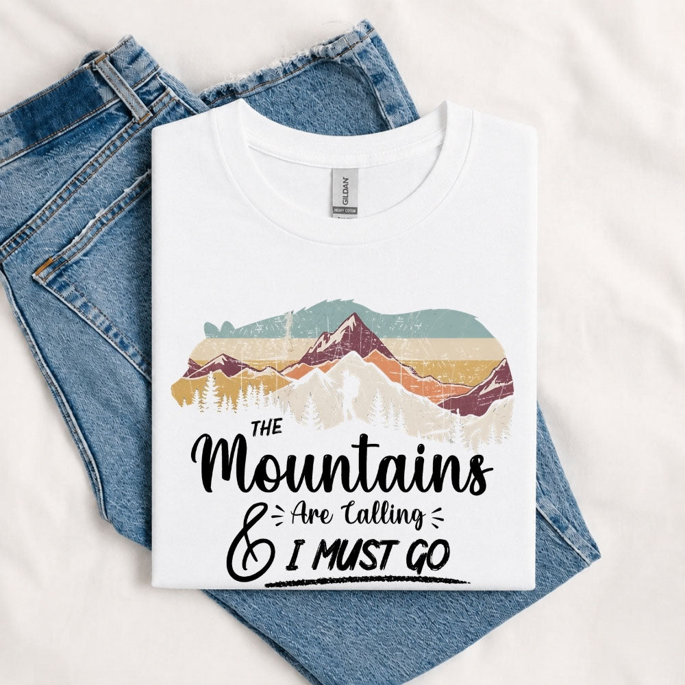 May include a White The Mountains Are Calling and I Must Go T-Shirt featuring an inspirational mountain graphic for hikers, campers, backpackers, and outdoor adventure lovers.